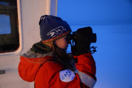 Katy Gavenus looks through binoculars at sea ice from the deck of the Akademic Federov icebreaker