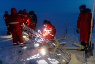 Setting up the meteorological tower. Matthew Shupe (CIRES) is in the foreground with headlamp. Photo: Mario Hoppmann/AWI scientists and equipment on ice