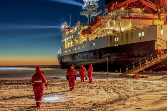 Polarstern ship frozen in ice, scientists in foreground