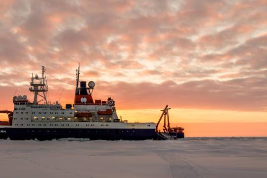 The Polarstern ship parked in Arctic ice at sunset.