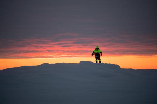 A polar bear guard stands atop a pressure ridge in residual ice